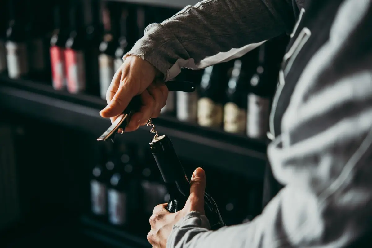 Inspiração de cantinho do vinho com estilo industrial, mostrando adega preta, prateleiras de cano de ferro e parede de tijolinhos aparentes.